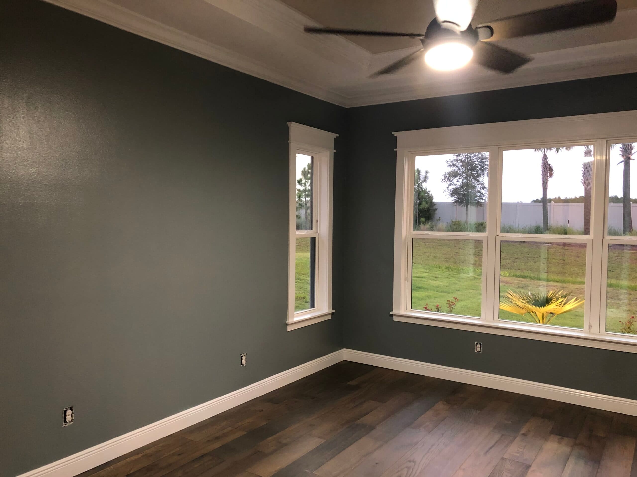 Custom home interior painted a deep gray-green with crisp white trim and crown molding